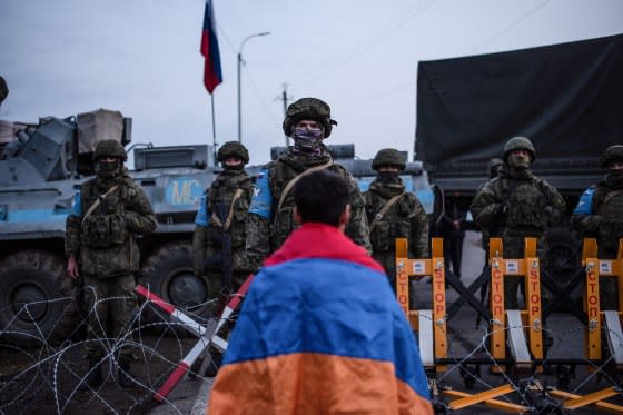 A protester wearing the Armenian national flag stands in front of Russian peacekeepers blocking the road outside Stepanakert, in Nagorno-Karabakh, on Dec. 24, 2022. <span class="copyright">Davit Ghahramanyan—AFP/Getty Images</span>