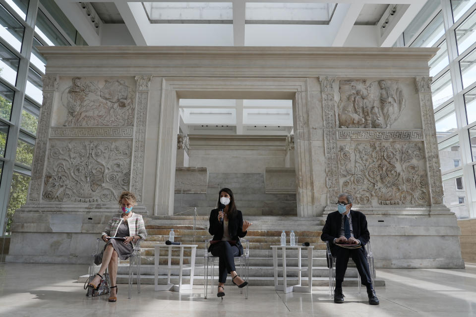 Rome's Mayor Virginia Raggi, center, backdropped by the Ara Pacis (Altar of Peace) presents to journalists an archeological finding emerged during the excavations at a Mausoleum in Rome, Friday, July 16, 2021. The monumental pomerial stone is dating back to Roman Emperor Claudio and was used to mark the ‘pomerium’ the sacred boundaries of the ‘Urbe’, the city of Rome, during the Roman empire. (AP Photo/Domenico Stinellis)