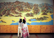 FILE PHOTO: People point to a map on a wall in Mount Kumgang resort in Kumgang September 1, 2011. REUTERS/Carlos Barria/File Photo