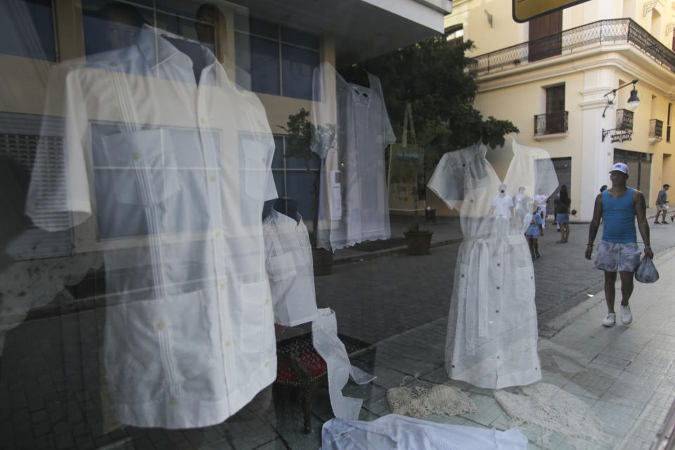 Camisas y vestidos de guayabera se exhiben a la venta en un escaparate en La Habana, Cuba, el domingo 26 de mayo de 2024. La guayabera fue creada en el siglo XVIII para los trabajadores agrícolas y con el tiempo se ha convertido en prenda formal y símbolo de Cuba. (Foto AP/Ariel Ley)