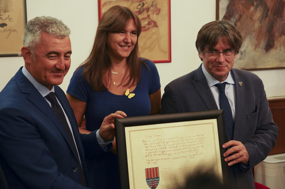 Catalan separatist leader Carles Puigdemont, right, flanked by Speaker of the Catalan Parliament Laura Borras exchanges gifts with Mayor of Alghero Mario Conoci, left, in Alghero, Sardinia, Italy, Saturday, Sept. 25, 2021. Puigdemont was visiting the city hall after he took a leisurely walk in the Sardinian city, waving to supporters, a day after a judge freed him from jail pending a hearing on his extradition to Spain, where the political firebrand is wanted for sedition. (AP Photo/Andrea Rosa)