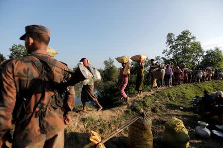 Rohingya refugees who fled from Myanmar walk past Bangladeshi border guards after crossing the border in Palang Khali, Bangladesh October 16, 2017. REUTERS/Zohra Bensemra