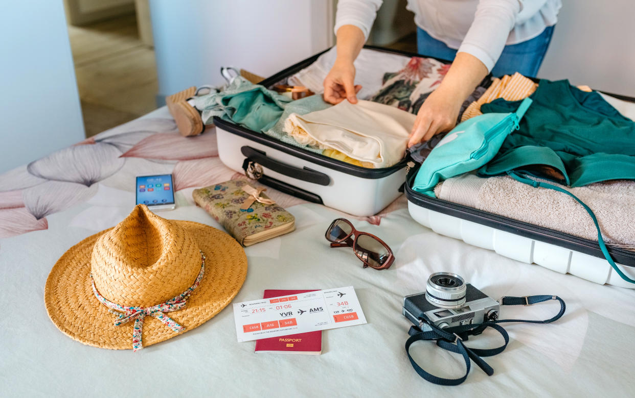 Unrecognizable woman preparing suitcase for summer holidays on the bed