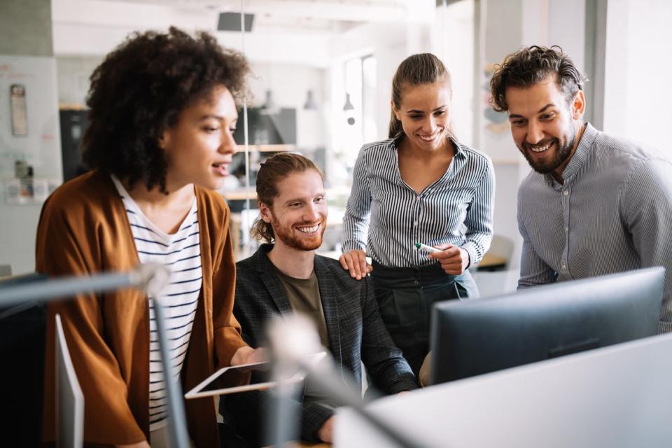 A group of investors smile and look at something on a computer.