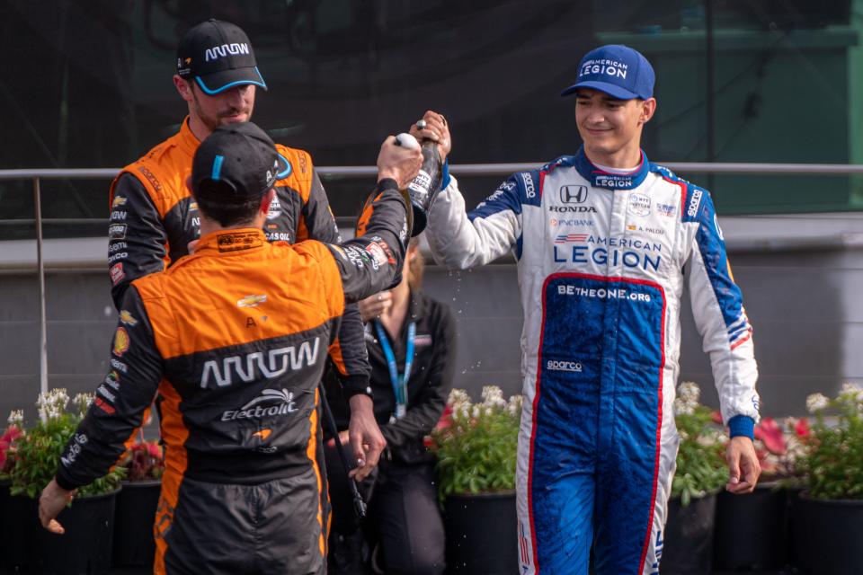 Chip Ganassi Racing driver Álex Palou (10), Arrow McLaren SP driver Pato O'Ward (5) and Arrow McLaren SP driver Alexander Rossi (7) toast their champagne bottles Saturday, May 13, 2023, during the celebration of the GMR Grand Prix at Indianapolis Motor Speedway. 