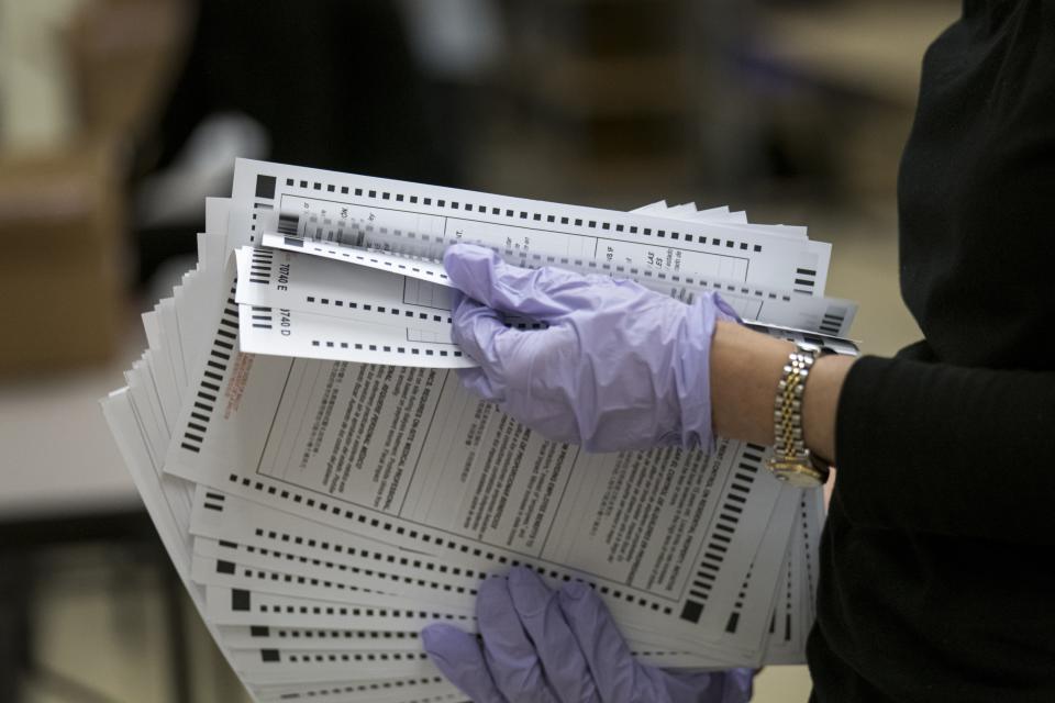 An election worker collects ballots while wearing protective gloves in Martinez, California, October 27, 2020.