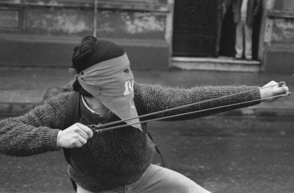 A protester aims a sling shot at police in Santiago, Chile, Sept. 1989. (AP Photo/Marco Ugarte)