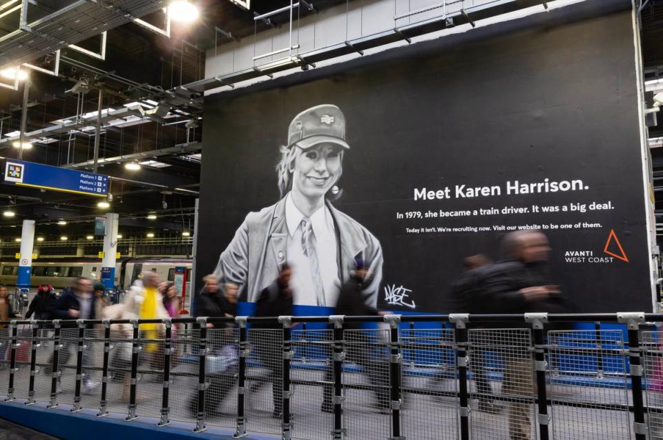Passengers walk past the new mural at Euston Station honouring Karen Harrison (PA)