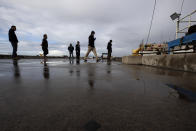 People keep their distance as they wait in line to buy fish from boat captain Nick Haworth, second from right, Friday, March 20, 2020, in San Diego. Haworth came home to California after weeks at sea to find a state all but shuttered due to coronavirus measures, and nowhere to sell their catch. A handful of tuna boats filled with tens of thousands of pounds of fish are now floating off San Diego's coast as they scramble to find customers. Haworth was selling on Friday to individuals for less than half what he would get from wholesalers. "This is a quarantine special," he joked. (AP Photo/Gregory Bull)