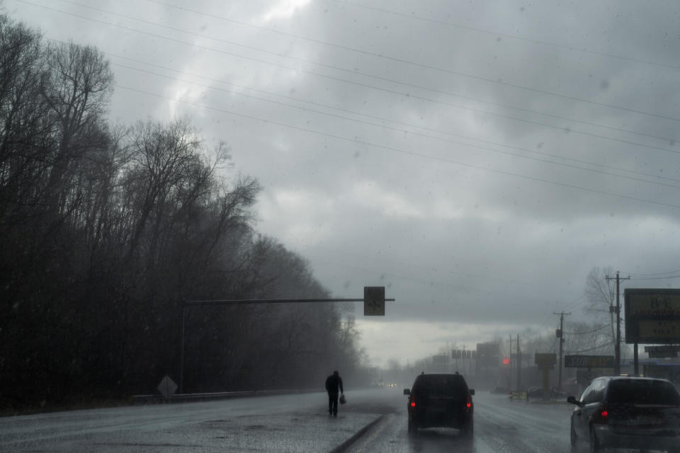 A man walks through a hail storm as the Quick Response Team's vehicle drives to visit another client who recently overdosed, Thursday, March 18, 2021, in Huntington, W.Va. Huntington was once ground-zero for this epidemic. Several years ago, they formed the team that within days visits everyone who overdoses to try to pull them back from the brink. It was a hard-fought battle, but it worked. The county's overdose rate plummeted. They wrestled down an HIV cluster. They finally felt hope. Then the pandemic arrived and it undid much of their effort: overdoses shot up again, so did HIV diagnoses. (AP Photo/David Goldman)