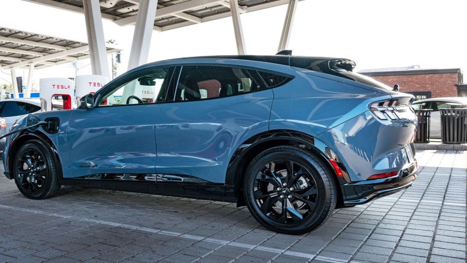 ford mustang mach e parked and charging at a tesla supercharger