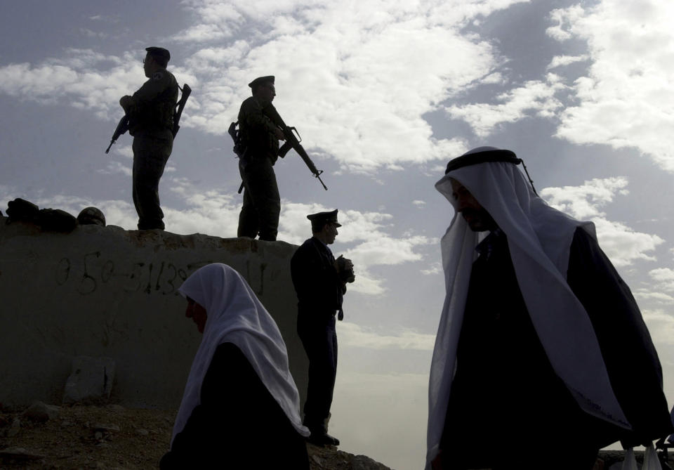 <p>Palestinians walk past Israeli border police, standing atop a block of stone, after crossing an Israeli army checkpoint between the West Bank town of Bethlehem and Jerusalem, Nov. 30, 2001. (Photo: Jacqueline Larma/AP) </p>