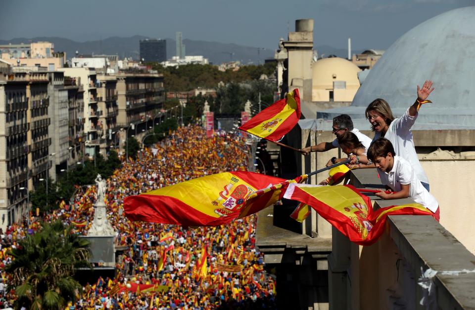 People on a rooftop wave Spanish flags during a march in downtown Barcelona, Spain, to protest the Catalan government's push for secession from the rest of Spain, Oct. 8, 2017. Sunday's rally comes a week after separatist leaders of the Catalan government held a referendum on secession that Spain's top court had suspended and the Spanish government said was illegal. 