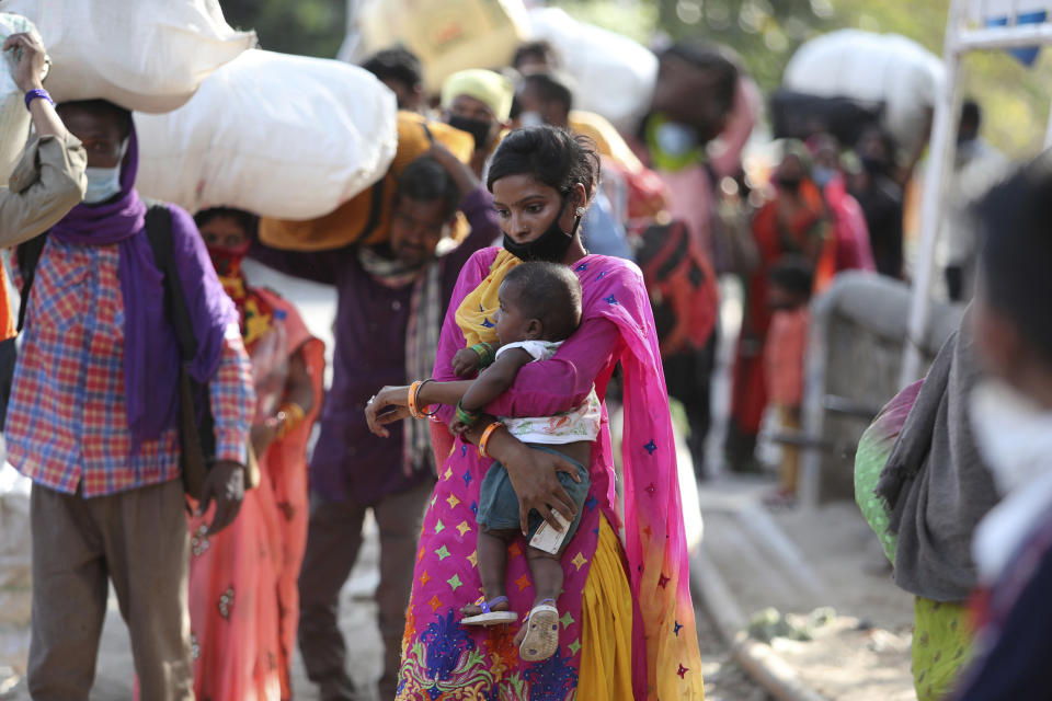 A woman holds a child and waits with other migrant workers outside a railway station hoping to be able to travel to their home states, in Jammu, India, Friday, May 22, 2020. India's lockdown was imposed on March 25 and has been extended several times. On May 4, India eased lockdown rules and allowed migrant workers to travel back to their homes, a decision that has resulted in millions of people being on the move for the last two weeks. (AP Photo/Channi Anand)