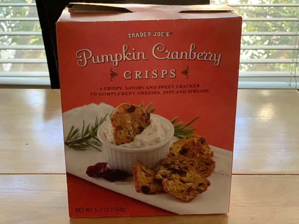 Orange box of Trader Joe's pumpkin cranberry crisps on a wooden table