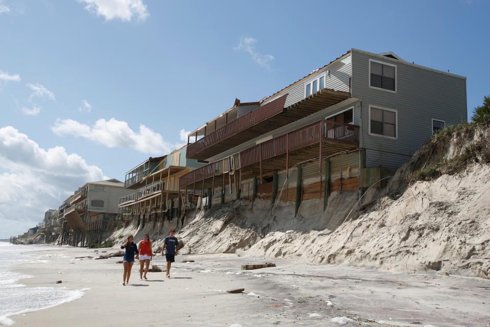 <p>People walk past damaged coastal houses after Hurricane Irma passed the area in Vilano Beach, Fla., Sept. 12, 2017. (Photo: Chris Wattie/Reuters) </p>