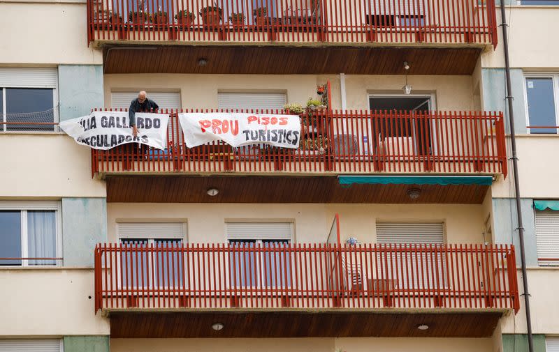 FILE PHOTO: A man ties protest banners in the balcony of a building that was recently converted for tourist use at Sants neighborhood in Barcelona