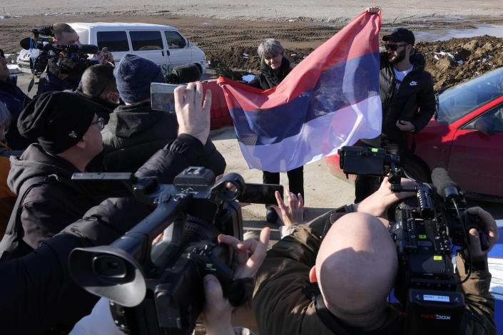 Fans with Serbian flag and journalist wait for arrival of Novak Djokovic in front of the VIP terminal at the Nikola Tesla airport in Belgrade, Serbia, Monday, Jan. 17, 2022. Djokovic is expected to arrive in the Serbian capital following his deportation from Australia on Sunday after losing a bid to stay in the country to defend his Australian Open title despite not being vaccinated against COVID-19. (AP Photo/Darko Vojinovic)