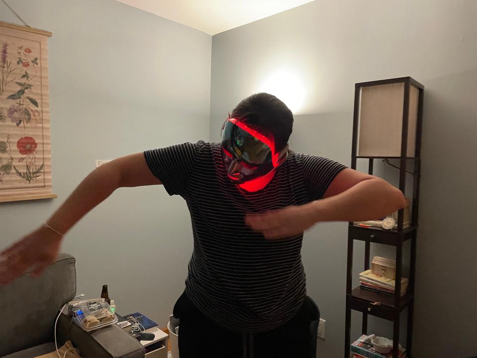 A person with an LED face mask does a robot dance.