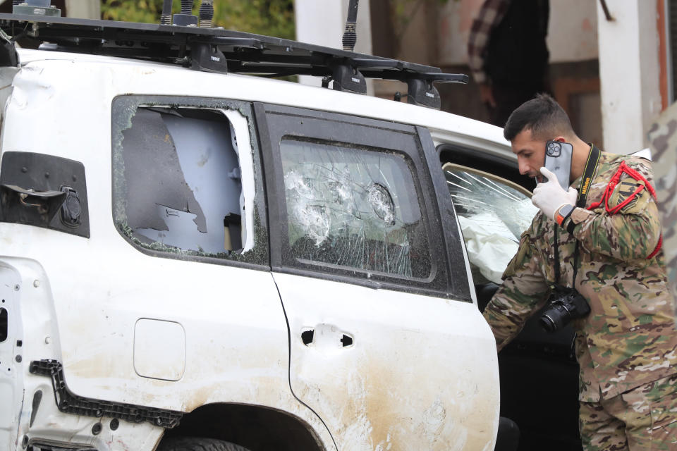 A Lebanese army investigator, talks on his phone as he checks a damaged UN peacekeeper vehicle at the scene where a UN peacekeeper convoy came under gunfire in the Al-Aqbiya village, south Lebanon, Thursday, Dec. 15, 2022. (AP Photo/Mohammed Zaatari)