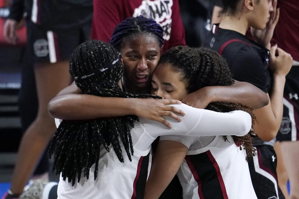 South Carolina forward Aliyah Boston, center, gets a hug from Stanford forward Francesca Belibi, left, and guard Haley Jones, right, after a women's Final Four NCAA college basketball tournament semifinal game Friday, April 2, 2021, at the Alamodome in San Antonio. Stanford won 65-66. (AP Photo/Eric Gay)