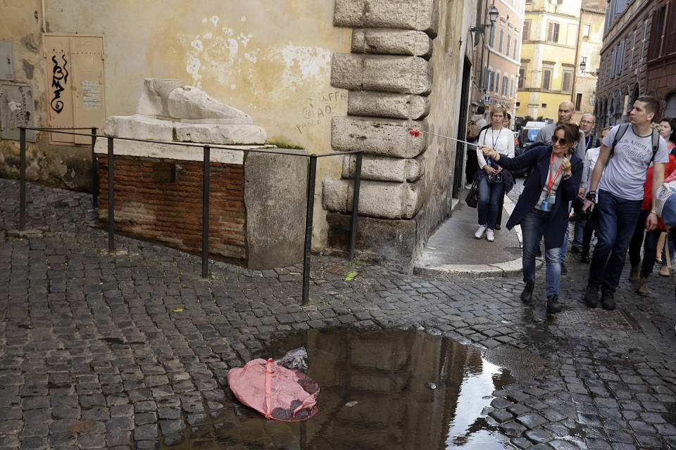 A tourist guide indicates to her group the monument of Pie’ di Marmo, a giant marble foot dating back to the 1st century, in an alleyway in Rome, Tuesday, Nov. 6, 2018. Rome’s monumental problems of garbage and decay exist side-by-side with Eternal City’s glories. (AP Photo/Gregorio Borgia)