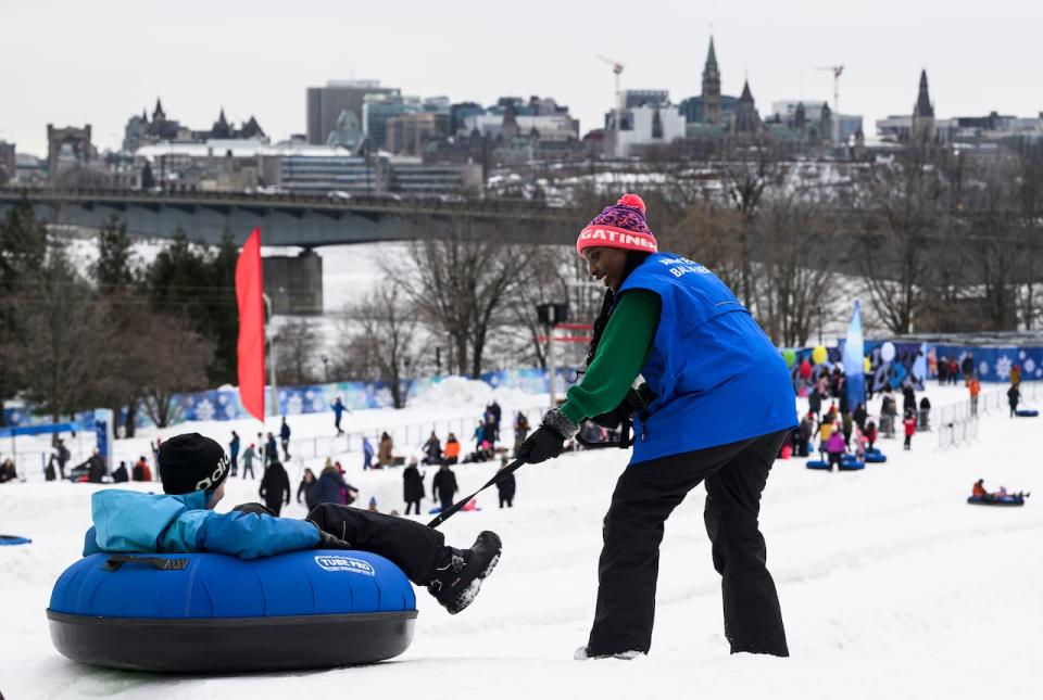 Carly Mushaha with the City of Gatineau launches a visitor down the ice slides at the Winterlude Snowflake Kingdom on its opening day, Feb. 3, 2024.