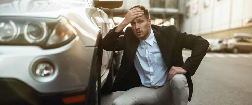 young handsome businessman looks nervous just had car crush in the middle of the road , unexpectable vehicle trouble