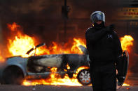 A riot police officer directs his colleagues to clear people away from a burning car last night in Clarence Road, Hackney.