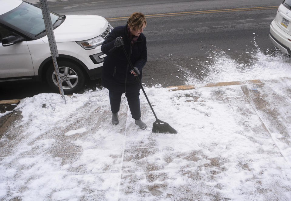 Judy Barket, of Pottsville, Pa., sweeps snow from the sidewalk in front of her business, Judy Barket Appraisal Services, in the 1900 block of West Market in Pottsville, Pa., on Monday, Feb. 11, 2019. (Andy Matsko/The Republican-Herald via AP)