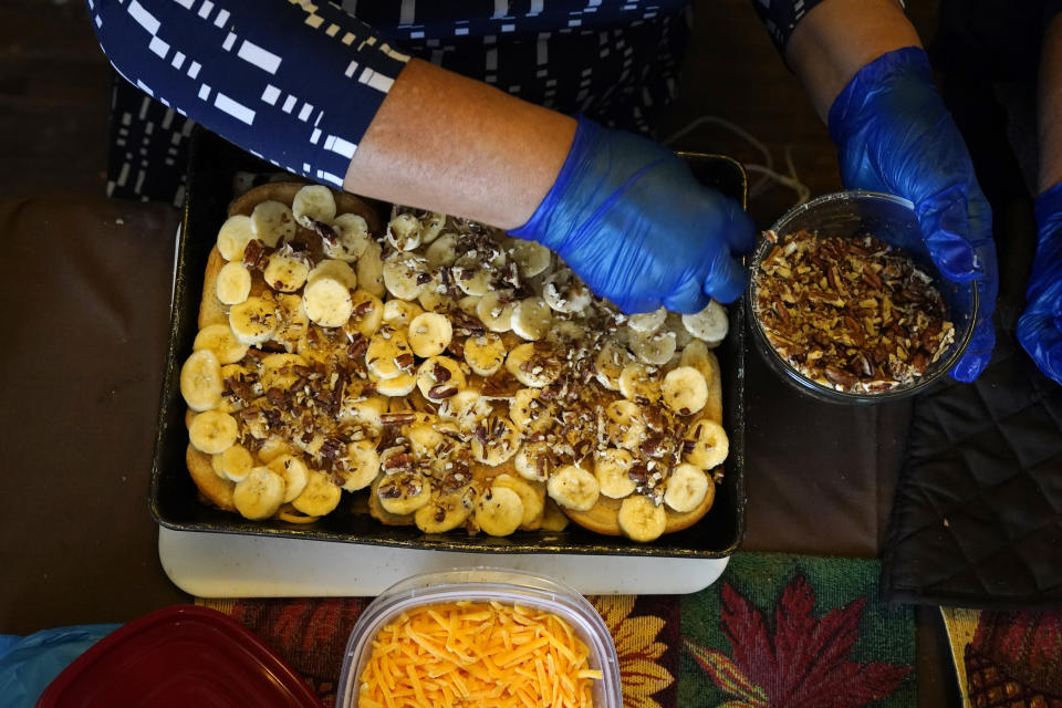 Olga Garcia prepares capirotada, a bread pudding layered with cheese, bananas, raisins, cinnamon and pecans, as she works on an afternoon family meal Wednesday, Nov. 4, 2020, in her home in Sedro-Woolley, Wash. On any other Thanksgiving, dozens of Olga's family members would squeeze into her home for the holiday. But this year, she'll deliver food to family spread along 30 miles of the North Cascades Highway in Washington state. If the plan works, everyone will sit down to eat in their own homes at precisely 6:30 p.m. and join a group phone call. (AP Photo/Elaine Thompson)