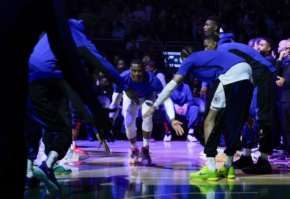 Clippers guard Russell Westbrook low-fives teammates during introductions before a preseason game against Utah.