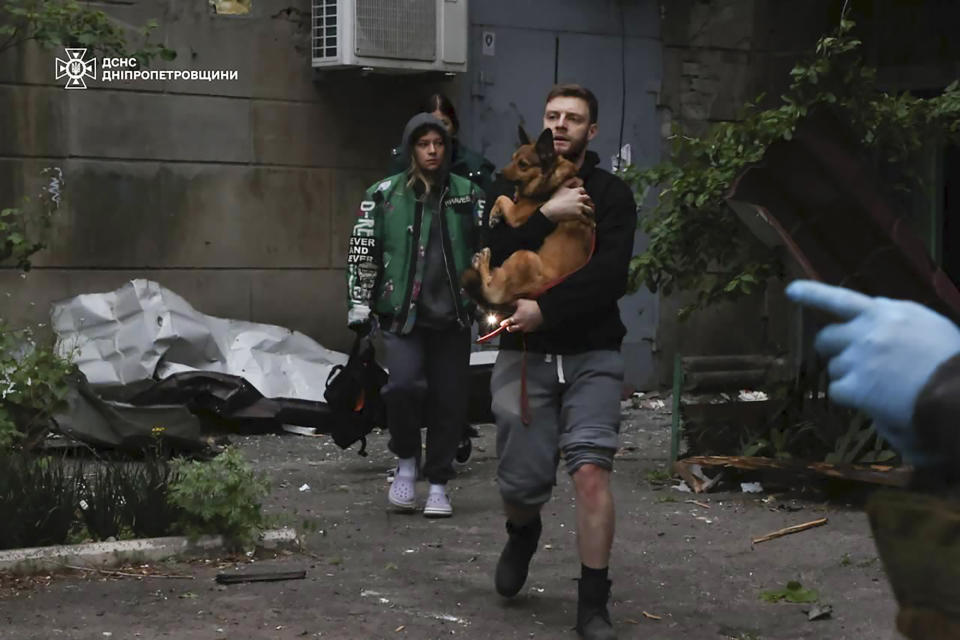 In this photo provided by the Ukrainian Emergency Service, local residents leave an apartment building, damaged after a Russian attack in Dnipro, Ukraine, Friday, April 19, 2024. (Ukrainian Emergency Service via AP Photo)