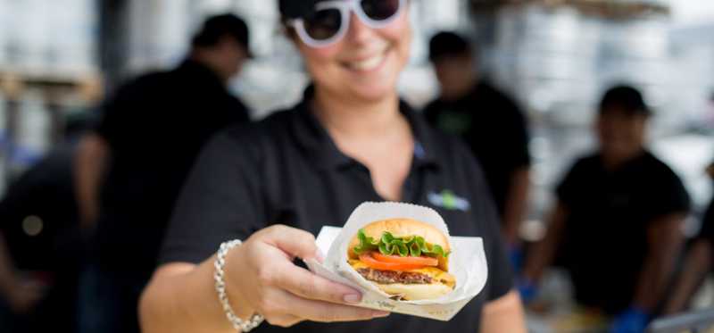 Shake Shack employee holding a burger.