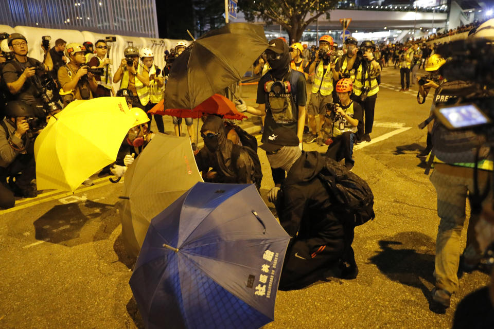 Black-clad protesters wearing goggles and masks hold umbrellas and stand outside government office in Hong Kong, Saturday, Sept. 28, 2019. Thousands of people gathered Saturday for a rally in downtown Hong Kong, belting out songs, speeches and slogans to mark the fifth anniversary of the start of the 2014 Umbrella protest movement that called for democratic reforms in the semiautonomous Chinese territory. (AP Photo/Vincent Thian)