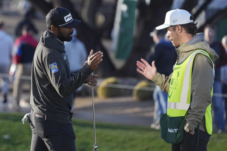 Sahith Theegala, left, slaps hands with his caddie Carl Smith, right, after finishing during the first round of the Phoenix Open golf tournament Thursday, Feb. 8, 2024, in Scottsdale, Ariz. (AP Photo/Ross D. Franklin)