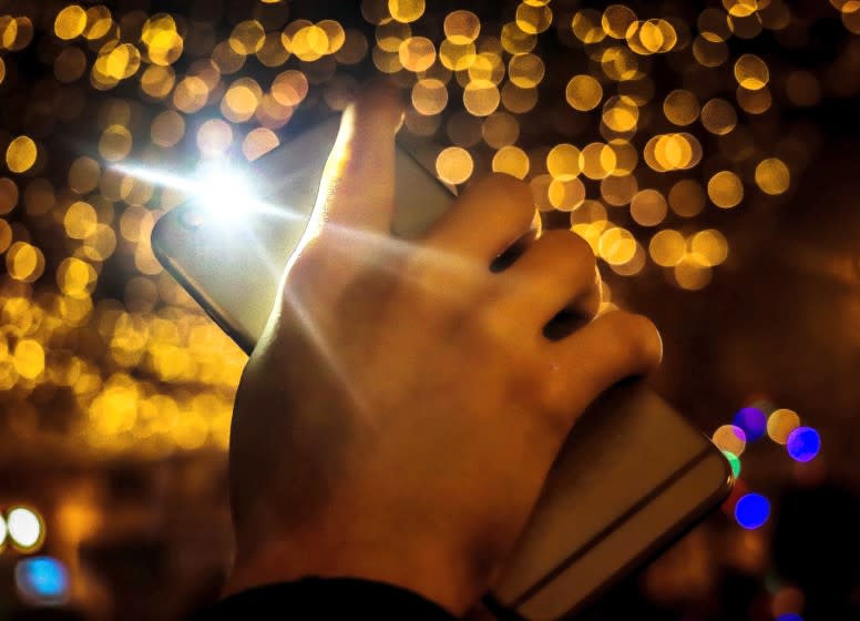 Cropped Hand Of Person Holding Mobile Phone With Illuminated Lights