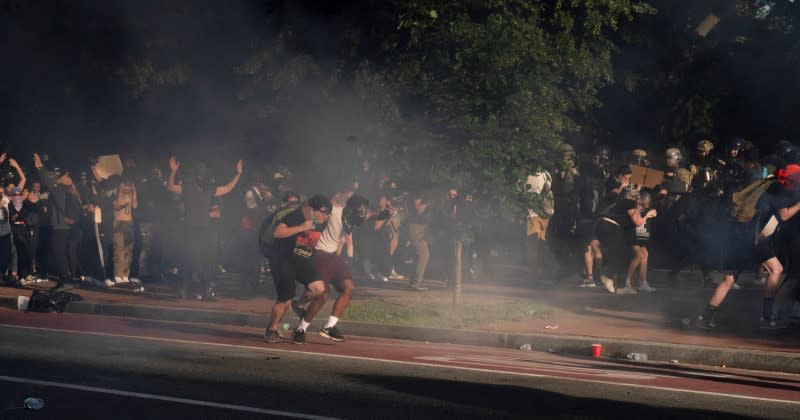 Protestors run as riot police clear Lafayette Park for a photo opportunity by President Donald Trump in Washington