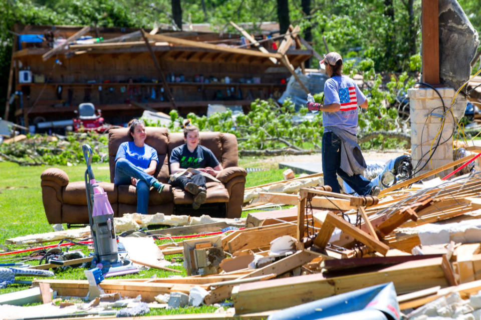 Rhonda Woods and her daughter, Annie, sit on a couch as Robin Black walks through the rubble of her home on Thursday, April 23, 2020, after a tornado ripped through the area in Onalaska, Texas. Several people were killed and up to 30 people were injured Wednesday as a tornado ripped through the small East Texas city, about 85 miles north of Houston. (Photo by Brett Coomer/Houston Chronicle via Getty Images)