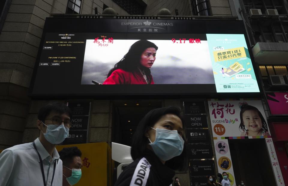 People walk past a huge TV screen showing movie "Mulan" at a downtown street in Hong Kong Thursday, Sept. 17, 2020. The remake of “Mulan” struck all the right chords to be a hit in the key Chinese market. Disney cast beloved actresses Liu Yifei as Mulan and removed a popular dragon sidekick in the original to cater to Chinese tastes. (AP Photo/Vincent Yu)