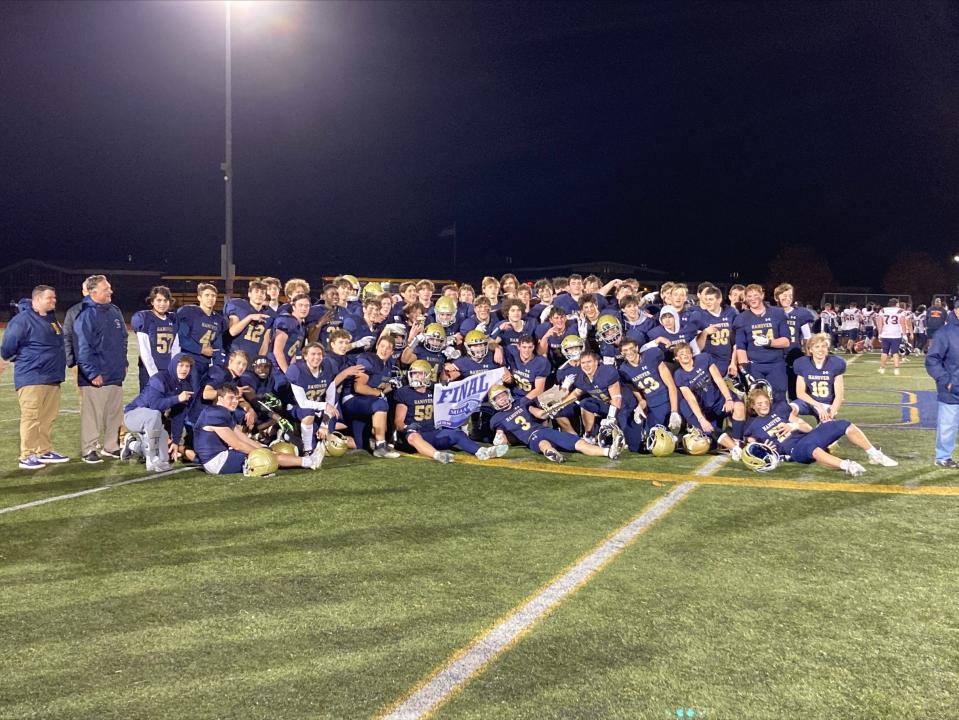 Hanover High football players celebrate with an MIAA banner proclaiming them to be a Division 3 Final Four team after beating Walpole, 40-37, in the quarterfinals on Thursday, Nov. 10, 2022.