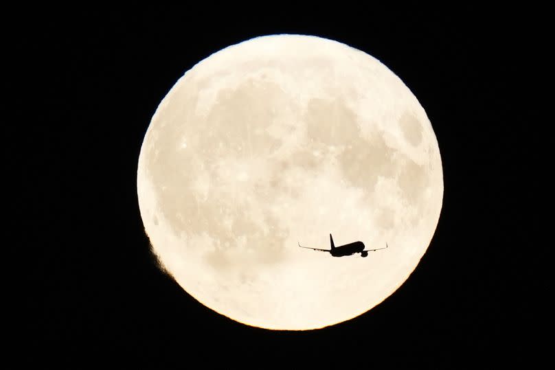 A plane passes by the supermoon over Copenhagen, Monday, Aug. 19, 2024.