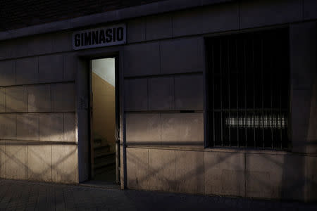 The headlights of a passing car in Madrid, Spain, February 14, 2019, illuminate the entrance to the gym of the school where Fernando Garcia-Salmones, 58, says he was raped by a priest almost 44 years ago. REUTERS/Susana Vera