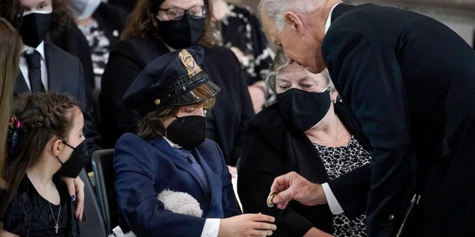 President Joe Biden presents a challenge coin to Logan Evans, son of slain US Capitol Police officer William Billy Evans at a ceremony at the US Capitol in Washington, DC on April 13, 2021.