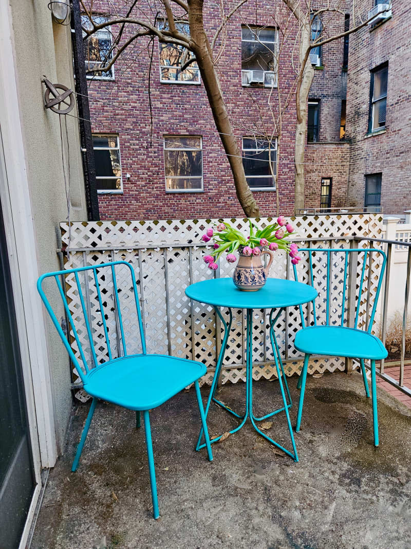 small patio/terrace with turquoise bistro set and vase of fresh tulips