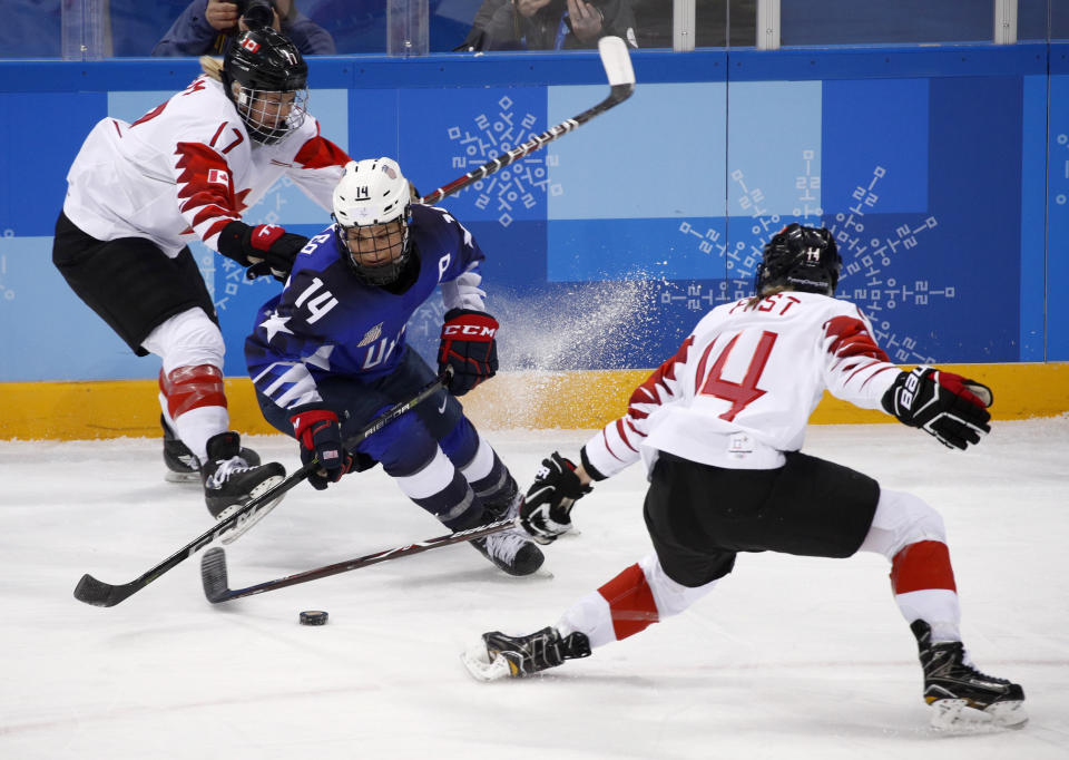 FILE - Brianna Decker (14), of the United States, skates with the puck away from Bailey Bram (17) and Renata Fast (14), of Canada, during the first period of the women's gold medal hockey game at the 2018 Winter Olympics in Gangneung, South Korea, Thursday, Feb. 22, 2018. Olympic gold medalist and six-time world champion Brianna Decker announced her retirement from the U.S. Women’s National Team, Thursday, March 2, 2023. (AP Photo/Jae C. Hong, File)