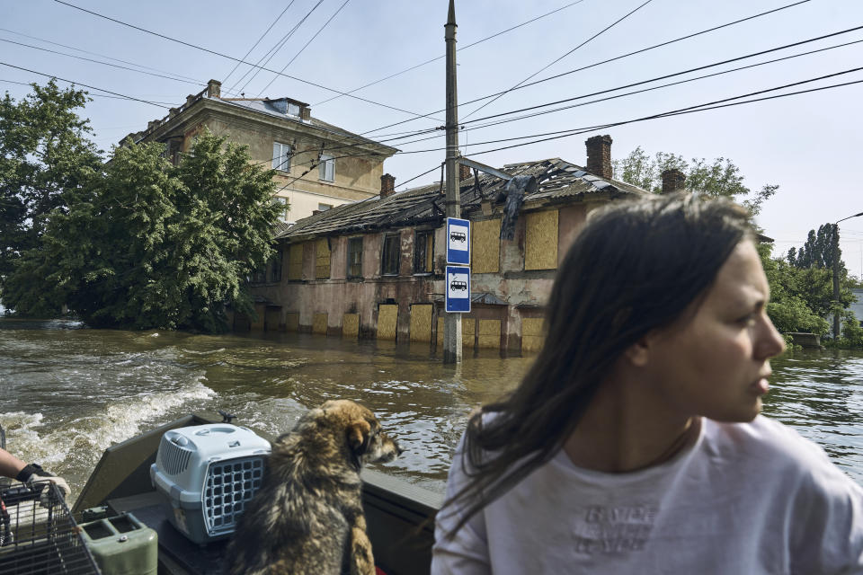 A Local resident with her pets evacuate on a boat from a flooded neighbourhood in Kherson, Ukraine, Thursday, June 8, 2023. (AP Photo/Libkos)