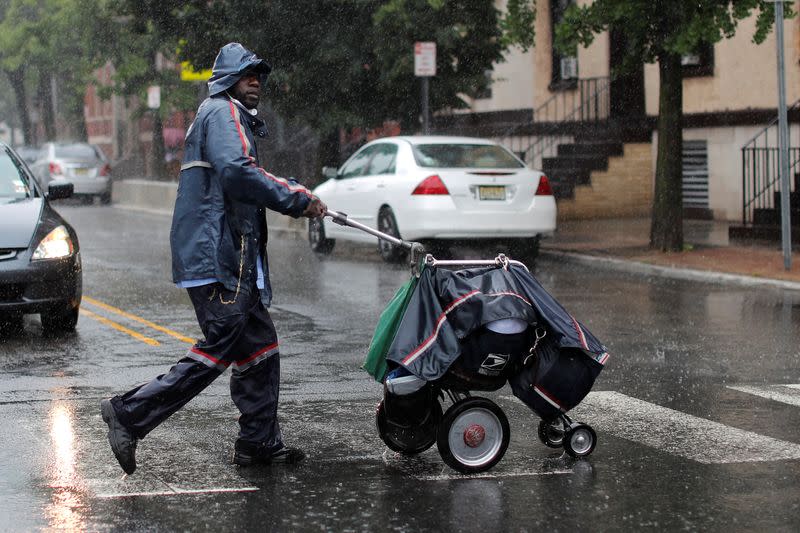 USPS Mail carrier walks through heavy rain as Tropical Storm Fay sweeps across northeastern United States in Jersey City