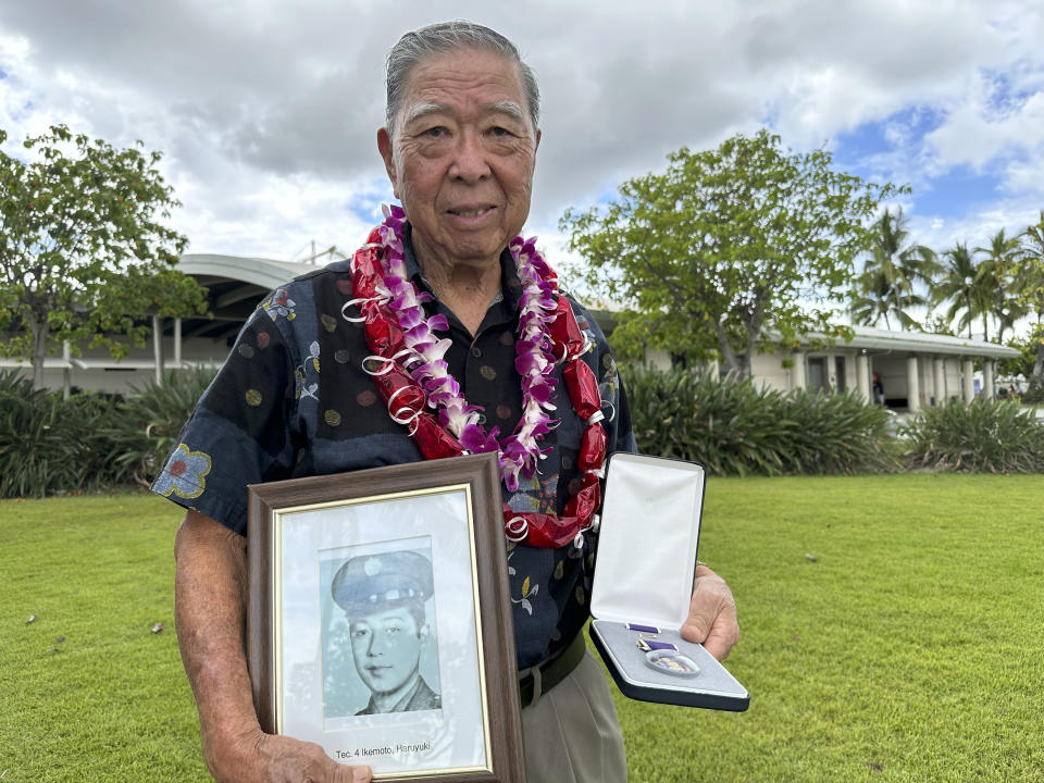 Wilfred Ikemoto holds a photo of his older brother, Haruyuki Ikemoto, and the Purple Heart medal posthumously awarded to him, in Pearl Harbor, Hawaii, on Friday, May 10, 2024. The families of five Hawaii men who served in a unit of Japanese-language linguists during World War II received posthumous Purple Heart medals on behalf of their loved ones on Friday, nearly eight decades after the soldiers died in a plane crash in the final days of the conflict. (AP Photo/Audrey McAvoy)