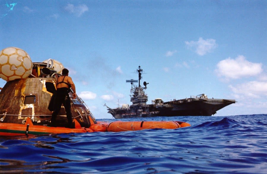 (19 Dec. 1972) — A water-level view of the Apollo 17 Command Module (CM) floating in the Pacific Ocean following splashdown and prior to recovery. The prime recovery ship, the USS Ticonderoga, is in the background. When this picture was taken, the three-man crew of astronauts Eugene A. Cernan, Ronald E. Evans and Harrison H. Schmitt, had already been picked up by helicopter and flown to the deck of the recovery ship. The spacecraft was later hoisted aboard the USS Ticonderoga. A United States Navy UDT swimmer stands on the flotation collar. Apollo 17 splashdown occurred at 1:24:59 p.m. (CST), Dec. 19, 1972, about 350 nautical miles southeast of Samoa.